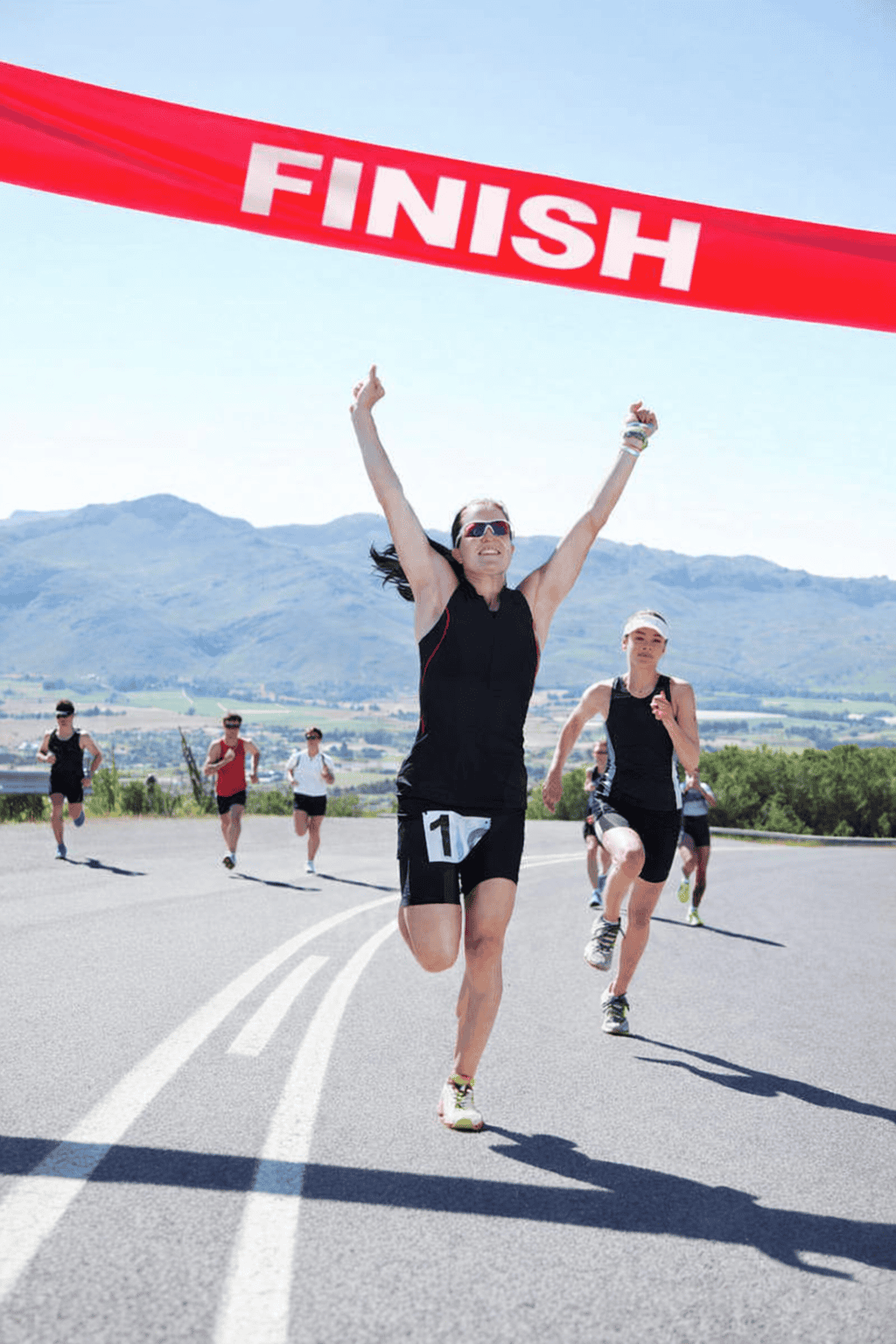 Image of a woman crossing the line in a running race finishing first.
