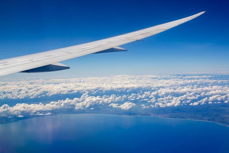 The joy of travelling. An airplane wing and the shoreline and beaches below.