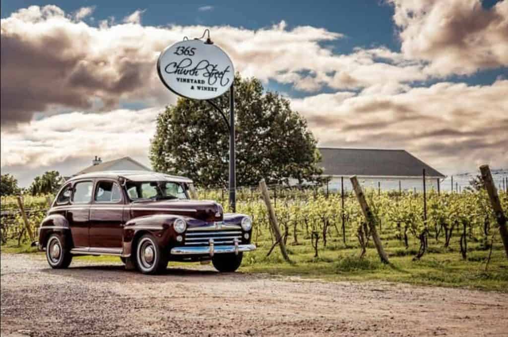 Classic vintage car parked near a vineyard under a cloudy sky at Atlantic Destinations.