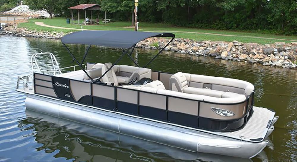 Seaside lighthouse overlooking lush green trees, sailboat on calm water near rocky shoreline, scenic coastal landscape in Atlantic destinations, perfect for boating and outdoor exploration.