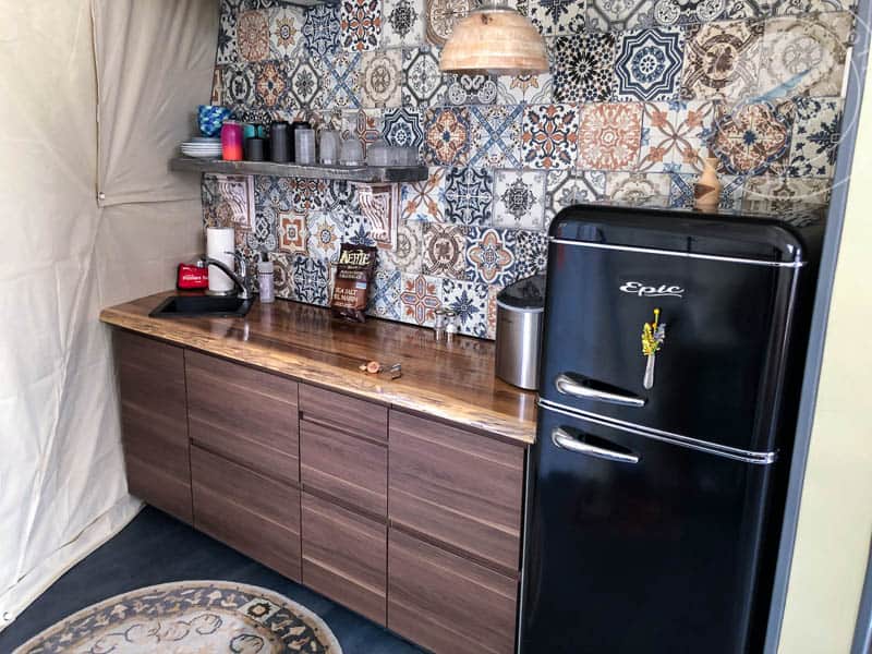 Retro kitchen with patterned tile backsplash, black vintage-style refrigerator, wooden countertop, coffee essentials, and cozy decor, perfect for Atlantic Destinations travel accommodations.