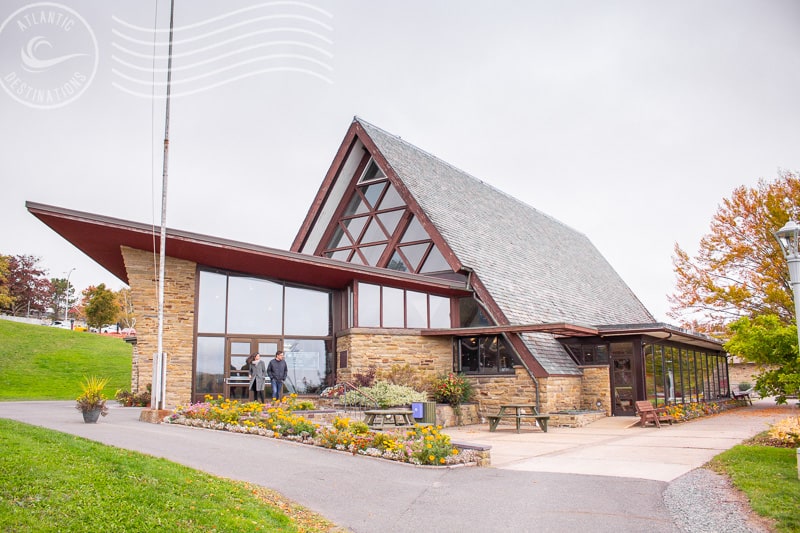 Charming Atlantic Destinations lodge with modern architectural design, surrounded by colorful autumn foliage and vibrant flower beds, perfect for a relaxing getaway.
