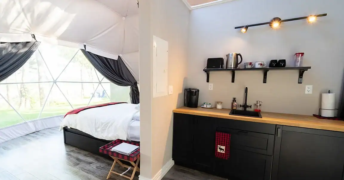Interior of one of the Gravity Luxury Domes, showing the bed and the kitchenette. Nova Scotia glamping domes.