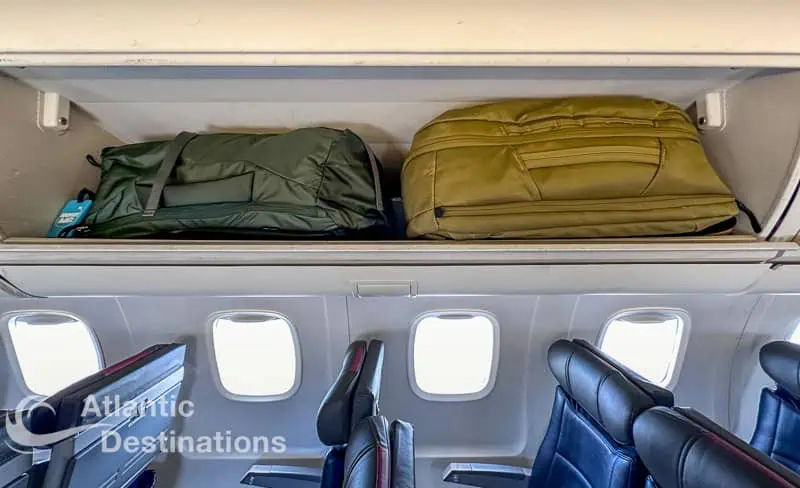 backpacks for air travel shown sideways in a small overhead airplane bin