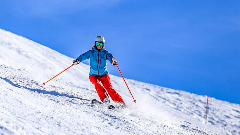 Things to do in North Carolina in winter - A skier dressed in blue and red gear glides down a snow-covered slope, perfect for winter sports enthusiasts seeking adventure and scenic mountain views.