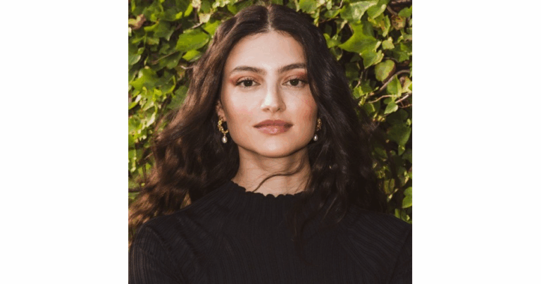 Elegant woman with long wavy hair in front of greenery for atomic insights.