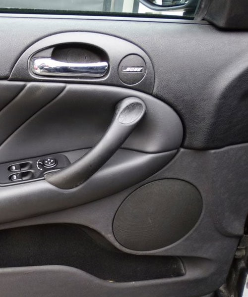 Bilde eines Autotür-Innenraums mit Lautsprecher und Bedienfeld für Fenstersteuerung.