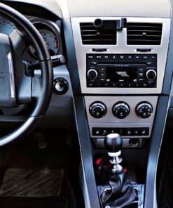 Autoszene mit Lenkrad, Armaturenbrett und Mittelkonsole, zeigt das Innere eines Fahrzeugs, inklusive Klimasteuerung und Radio.