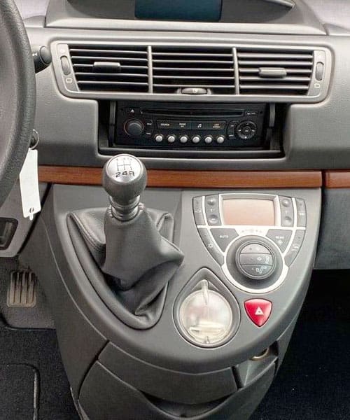 Alter Text: Innenansicht eines Auto-Dashboards mit Schalthebel und Klimasteuerung.