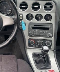 Hauptbild: Innenraum eines Autos mit Radio- und KlimakontROLLEN, Manuelle Schalttafel, Fahrzeuginstrumente sichtbar.