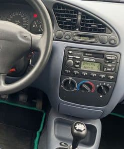 Altes Autoradio im Fahrzeugdashboard, mit Kassettenspieler und manuellen Klimareglern.