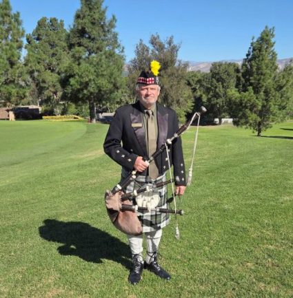 Man standing on a golf course holding archery equipment.
