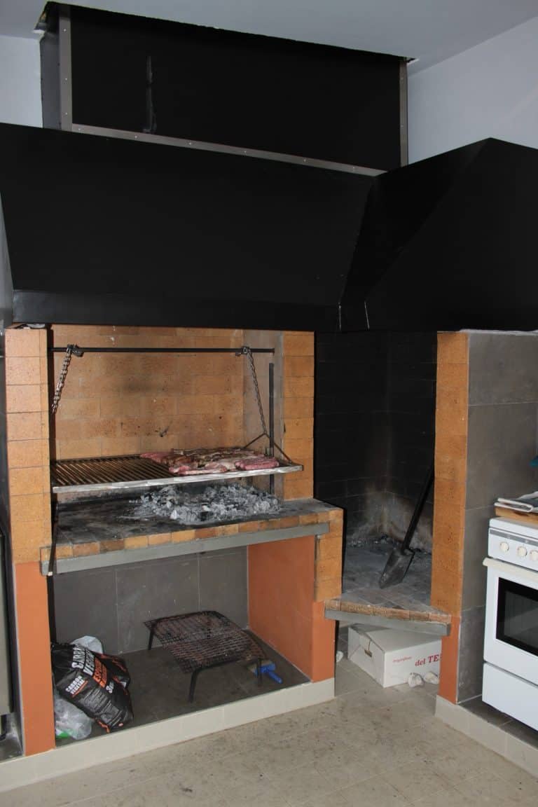 Parrilla de interior con carne asándose al carbón