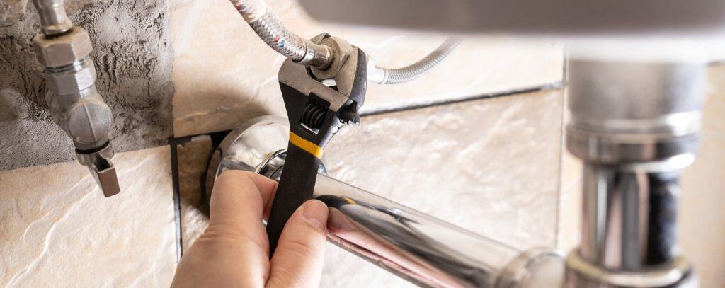 Persona reparando tubería con llave inglesa