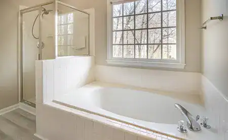 Baño con ducha y bañera junto a ventana grande