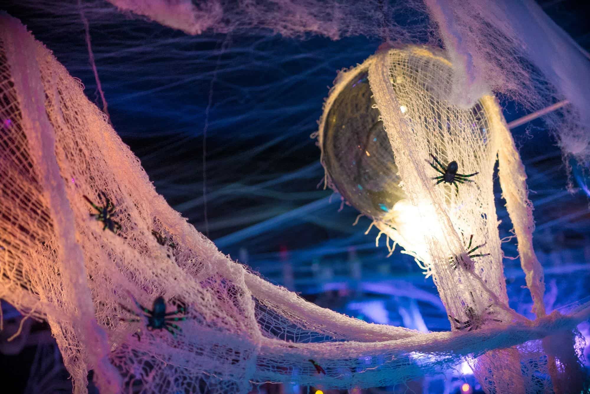 Haunted Halloween decoration with spider and torn fabric in eerie lighting.