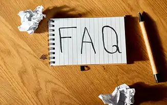 Controversial F-A-Q concept on lined notebook with crumpled paper and pen, highlighting digital marketing FAQs.