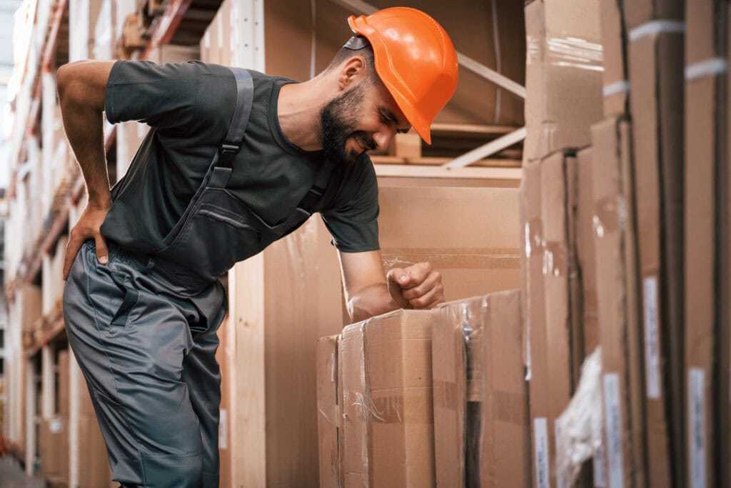 Worker with safety helmet inspecting boxes to prevent muscle injuries in the workplace.
