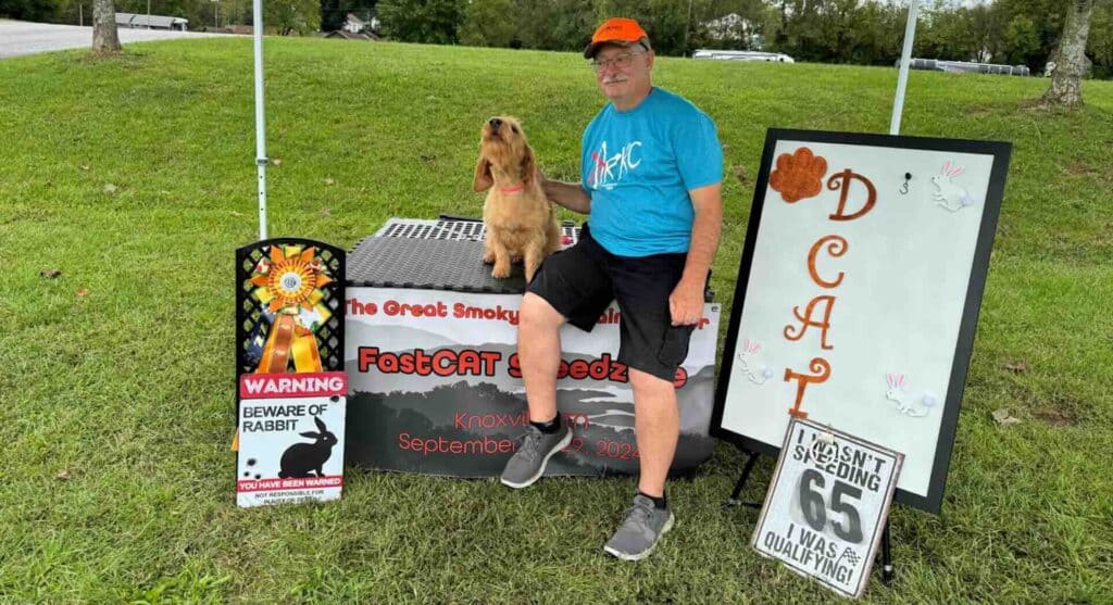 Man with dog at FastCAT speed event table.