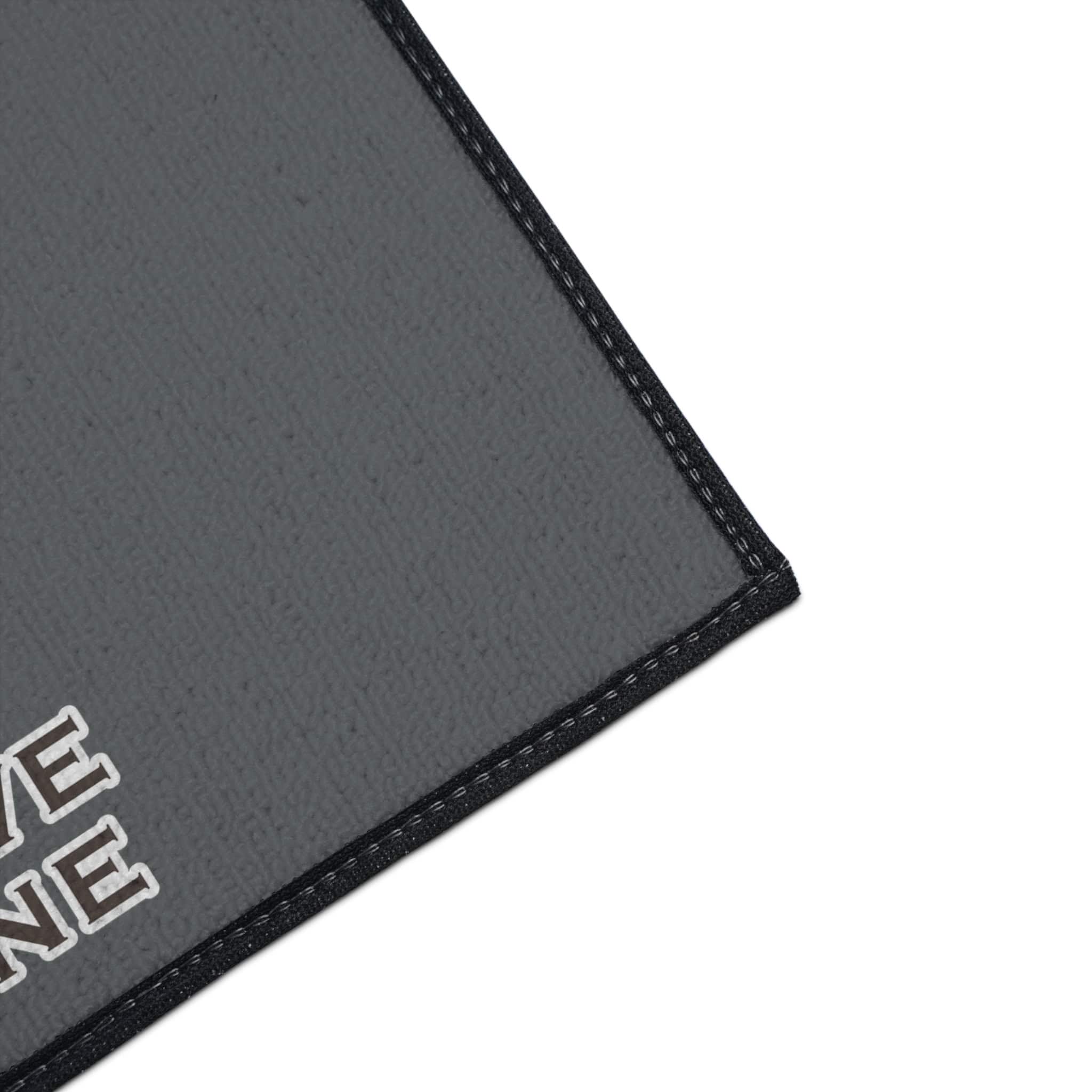 Gray doormat with black border and text design.
