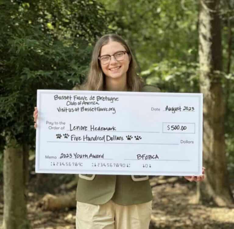 BfdBCA Youth Award 2022 winner holding large award check in front of some trees.
