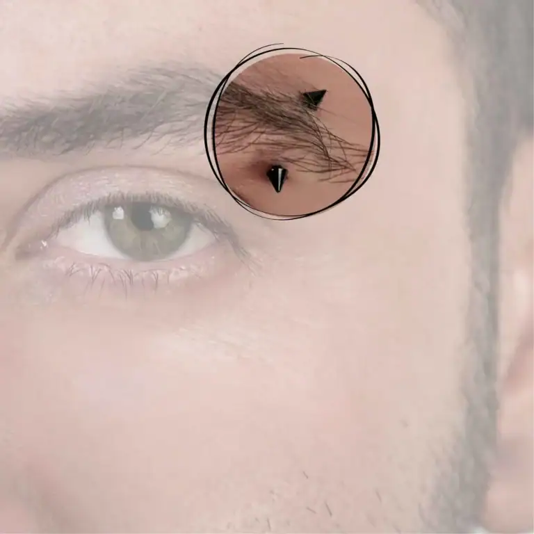 Ein auffälliges Augenbrauenpiercing, das die Augenbraue betont, unterstrichen durch einen schwarzen Schmuck, der elegant um den Brauenbogen verläuft und Ihrem Look eine markante Note verleiht.