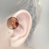 Detailaufnahme eines Anti-Helix Piercings am inneren Rand der Ohrmuschel, verziert mit einem kleinen, glänzenden Ring für eine dezente Eleganz.