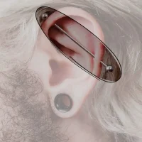 Industrielles Ohrpiercing, das mit einer geraden Barbell zwei Punkte des Knorpels verbindet, kreiert einen markanten und kühnen Look entlang der Ohrkante.