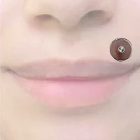 Ein Monroe-Piercing, platziert über der Oberlippe links, inspiriert von Marilyn Monroes legendärem Schönheitsmal, verziert mit einem schimmernden Schmuckstein, der klassische Eleganz ausstrahlt.