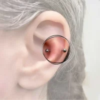 Detailaufnahme eines Snug-Piercings, eingefasst im inneren Bereich der Ohrmuschel für einen einzigartigen und auffälligen Look, akzentuiert mit einem kleinen, schimmernden Schmuckstück.