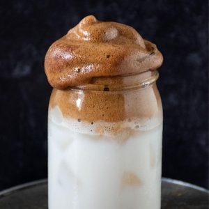 Whipped coffee over iced almond milk in a Mason jar