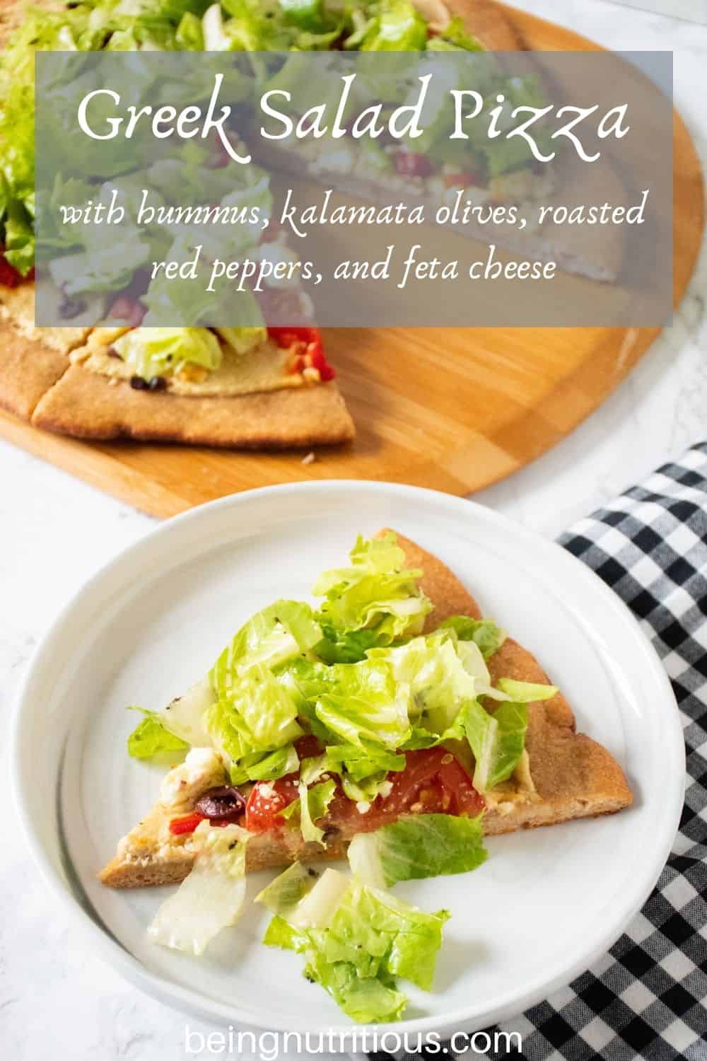 Slice of pizza on a plate. In background is the rest of the pizza on a peel, with whole wheat crust, topped with salad. Text overlay: Greek Salad Pizza with hummus, kalamata olives, roasted red peppers, and feta cheese.