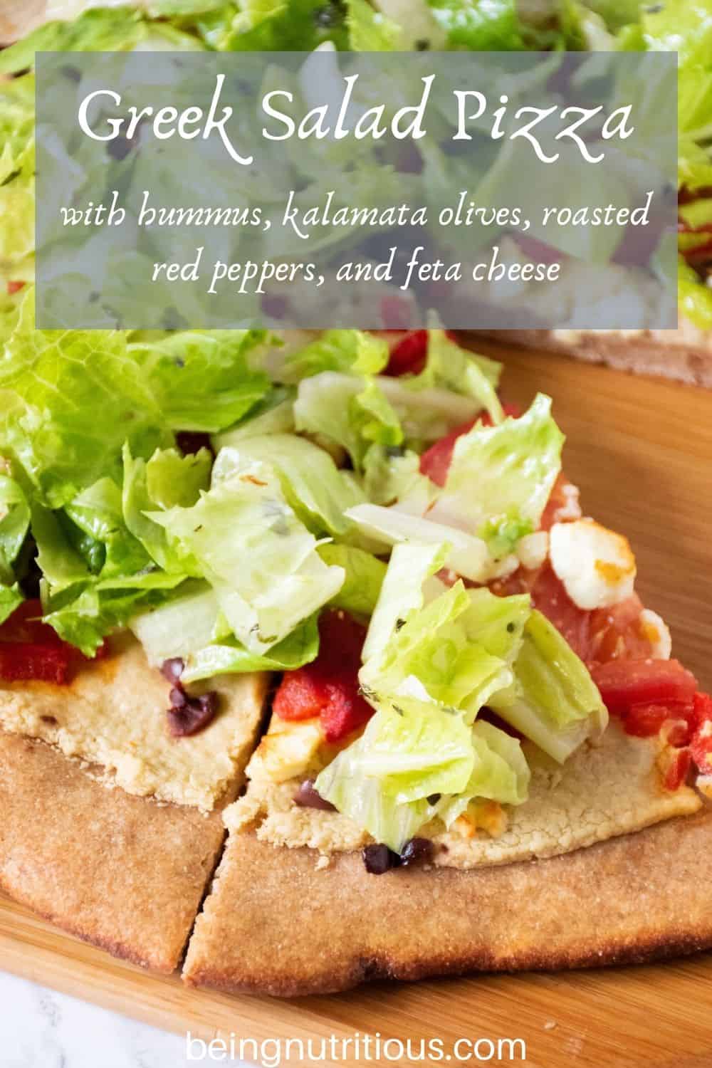 Pizza on a peel, with whole wheat crust, topped with salad. Text overlay: Greek Salad Pizza with hummus, kalamata olives, roasted red peppers, and feta cheese.