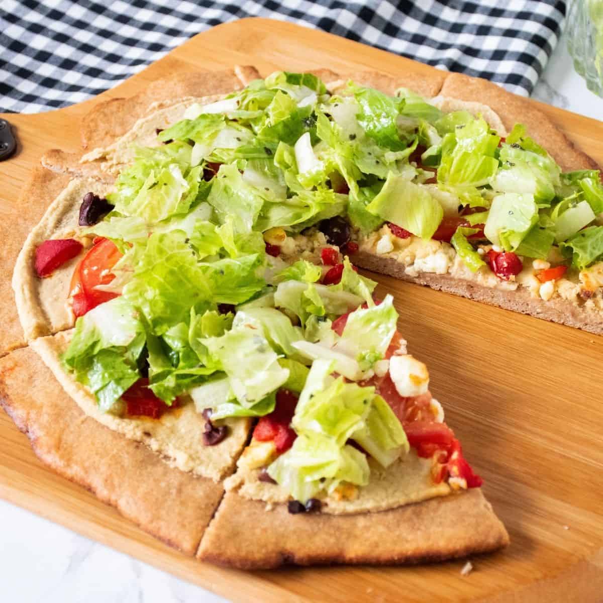 Pizza on a peel, with whole wheat crust, topped with salad.
