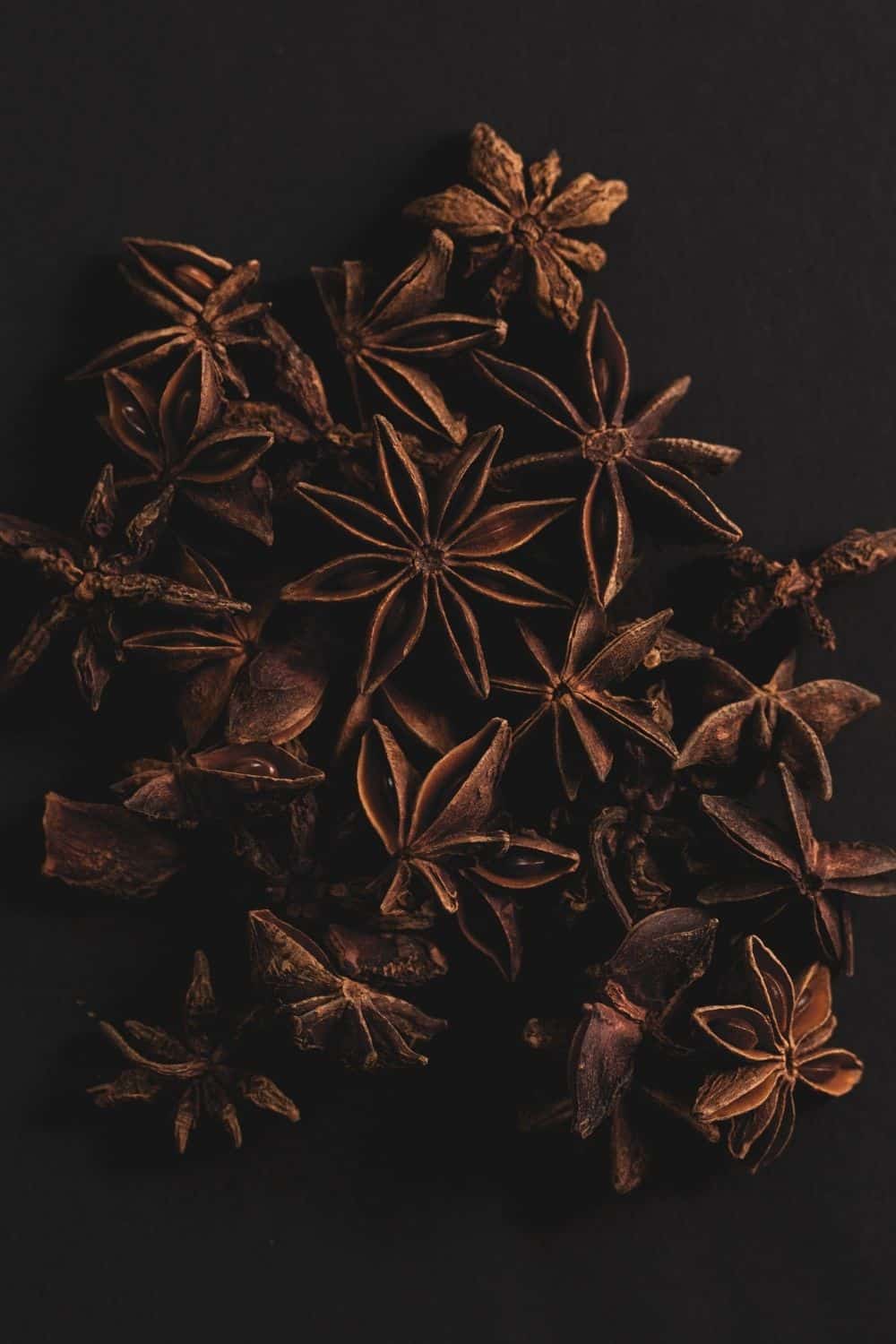 Many star anise pods on a dark background.