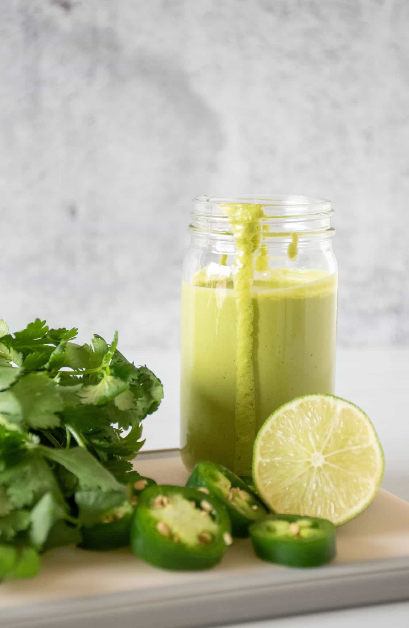 Small jar of green sauce, with ingredients around it.