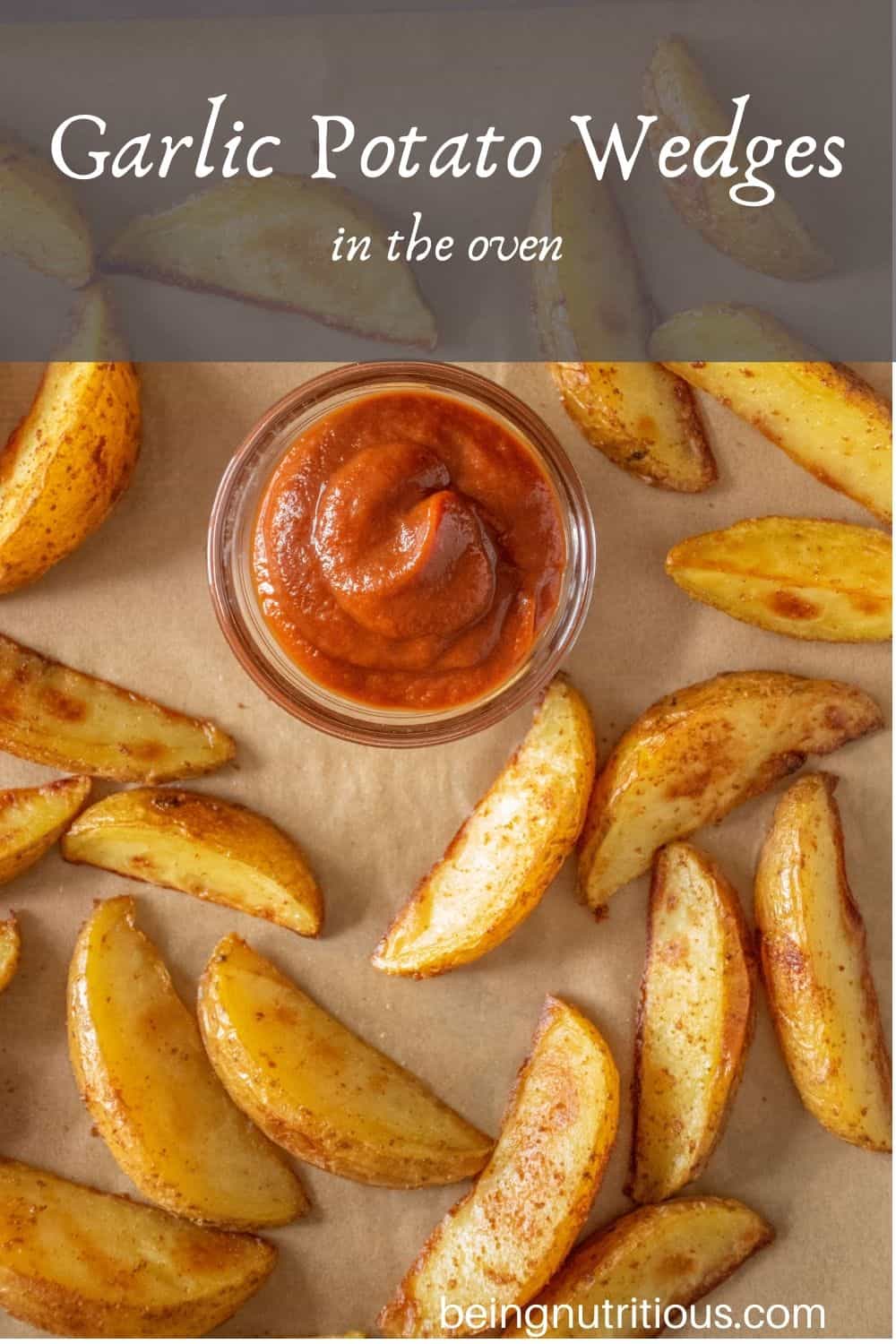 Basket of potato wedges with a small bowl of ketchup. Text overlay: Garlic Potato Wedges in the Oven.