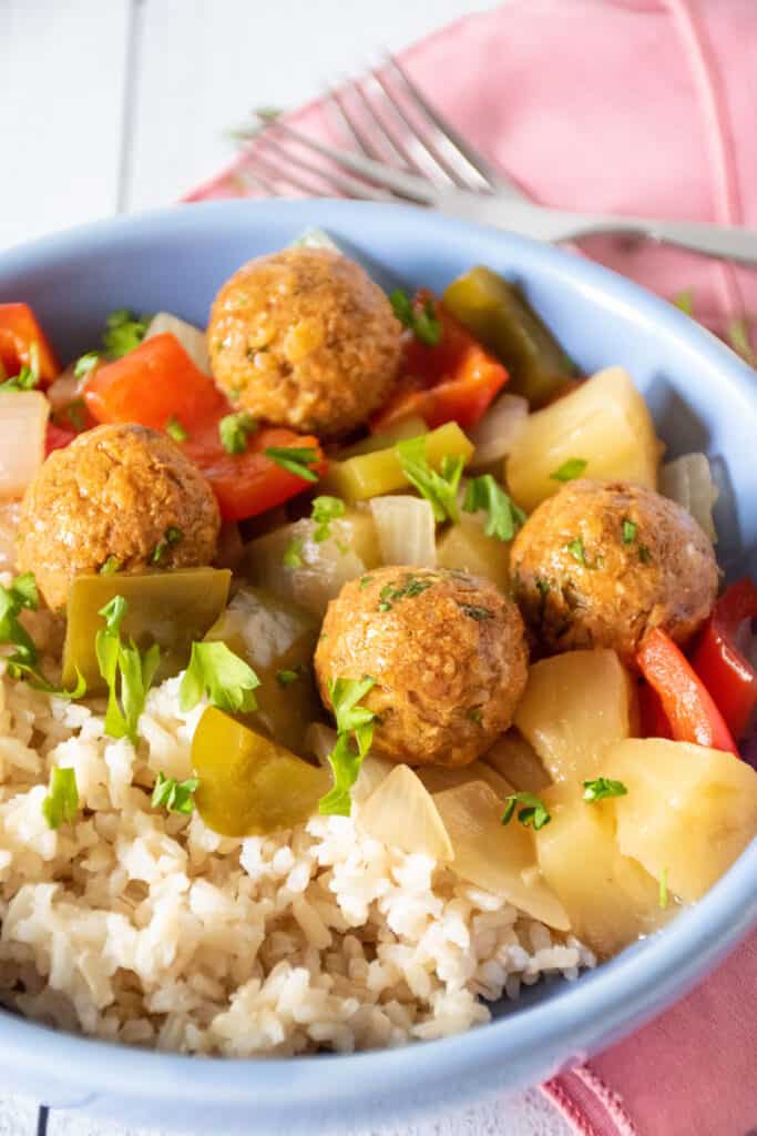 Bowl with rice, meatballs, and onions and bell peppers.