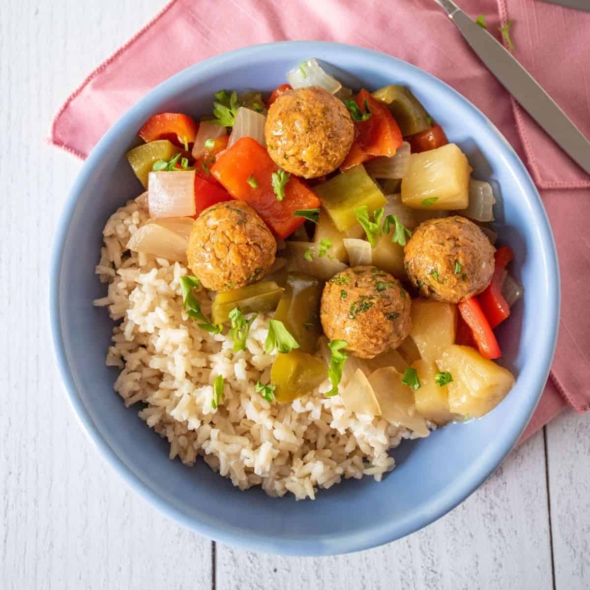 Bowl with rice, meatballs, and onions and bell peppers.
