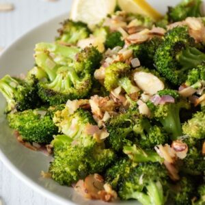 Plate of roasted broccoli with almond topping.