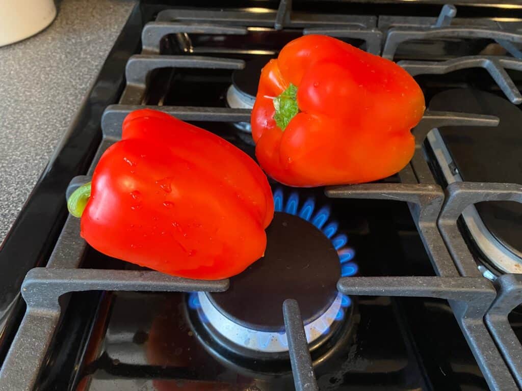 Fresh red bell peppers on a stove grate.