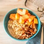 Overhead picture of a bowl of oats, with chopped pecans and papaya.