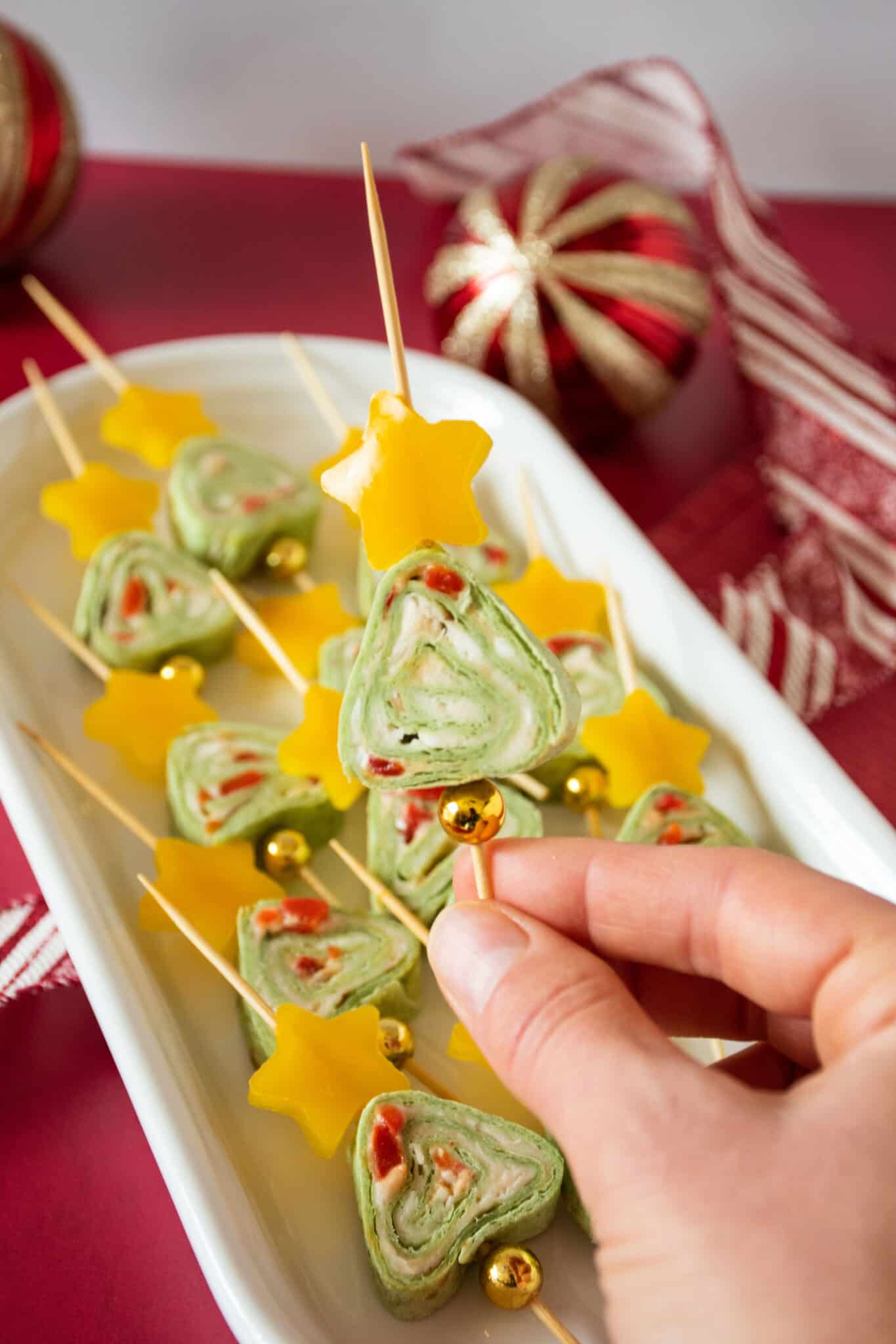 Green tortilla roll up appetizers shaped like a Christmas tree. One being held up to see.