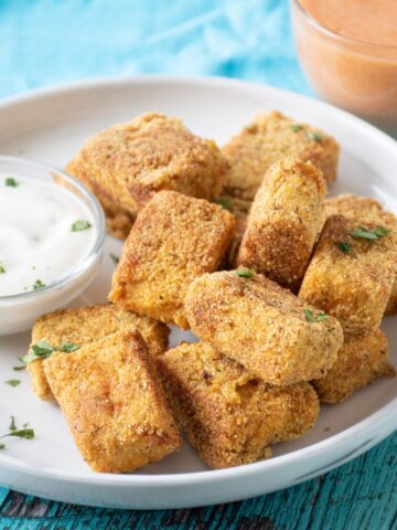 Crispy tempeh appetizers on a plate with ranch dressing in a small bowl.