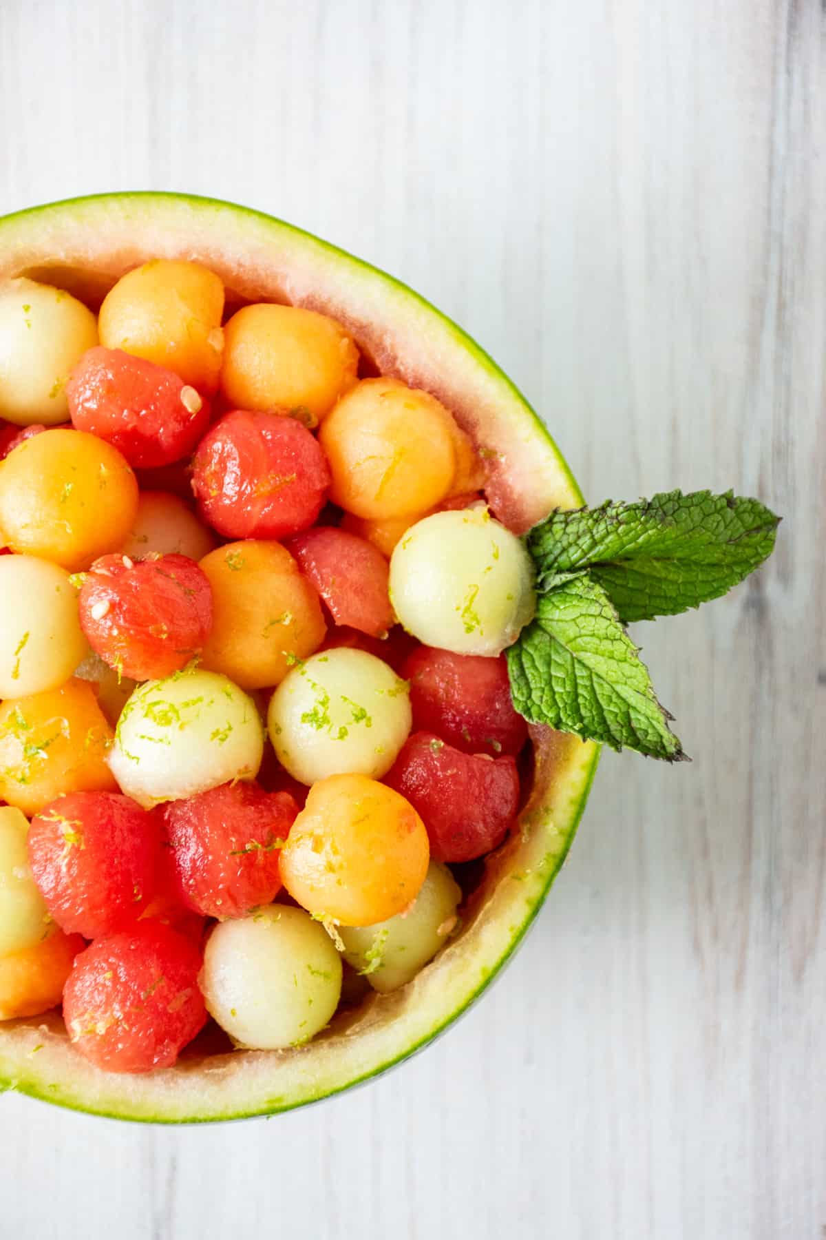 Overhead image of balls of melon in a watermelon bowl