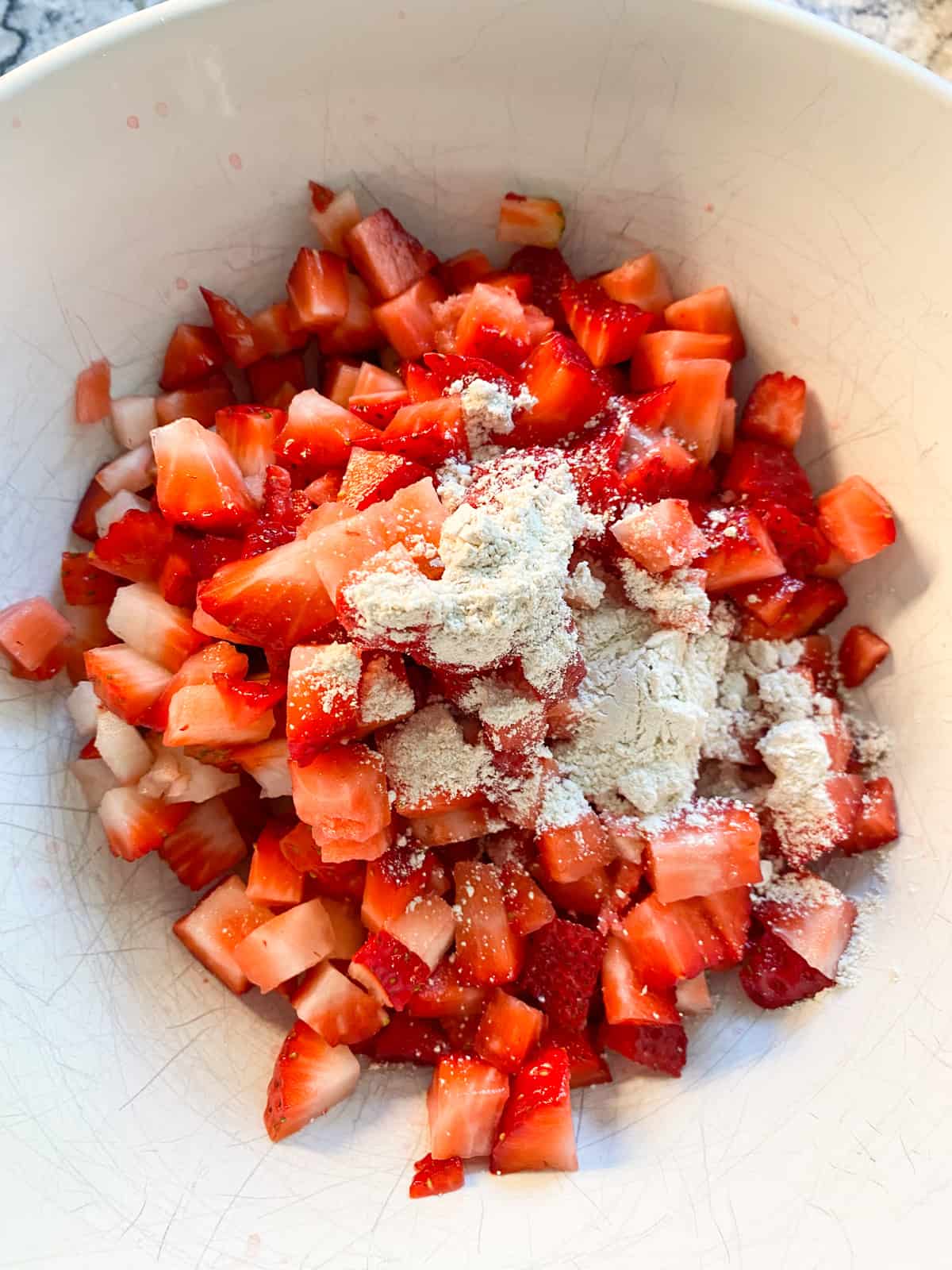 Bowl of diced strawberries with flour on them.