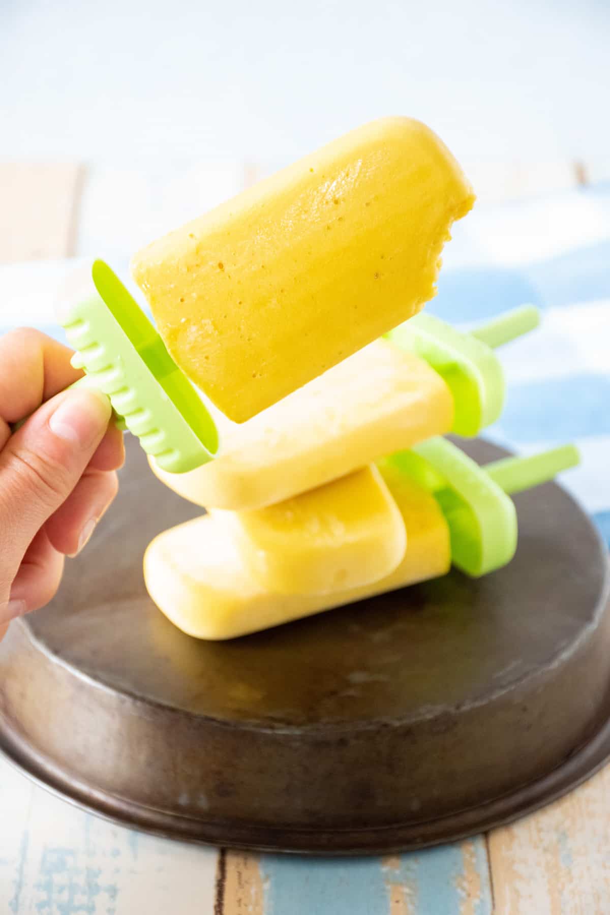 Hand holding up a popsicle, with a bite taken out of it.