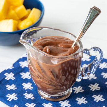 Small glass pitcher of chocolate sauce.