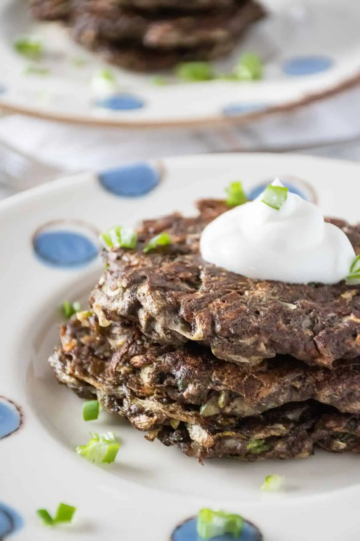 Stack of 3 gluten free zucchini fritters with a dollop of plain Greek yogurt on top.