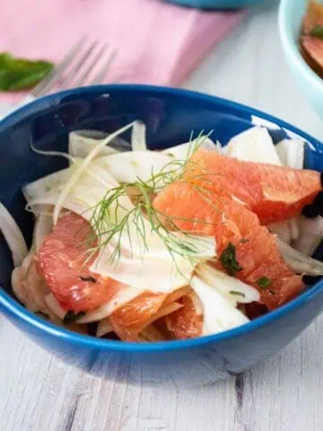 Salad with citrus and fennel in a small bowl, garnished with a fennel frond.